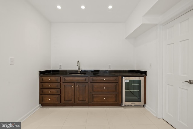 bar featuring sink, light tile patterned floors, beverage cooler, and dark brown cabinets