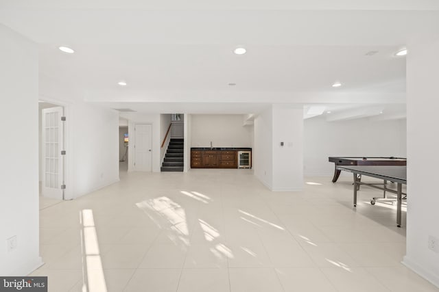 unfurnished living room with bar, light tile patterned flooring, and wine cooler