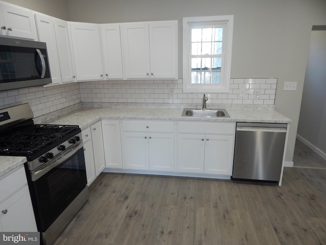 kitchen with stainless steel appliances, white cabinets, and hardwood / wood-style flooring