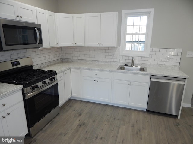 kitchen with white cabinets, sink, tasteful backsplash, appliances with stainless steel finishes, and hardwood / wood-style floors