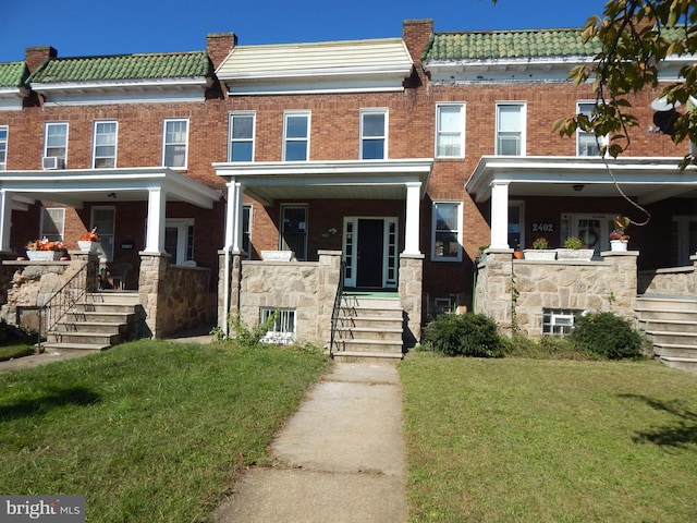 multi unit property featuring a front yard and covered porch