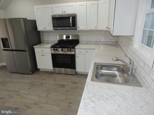 kitchen featuring dark hardwood / wood-style flooring, sink, decorative backsplash, appliances with stainless steel finishes, and white cabinetry