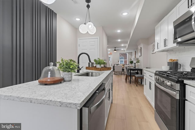 kitchen featuring white cabinets, sink, a kitchen island with sink, light hardwood / wood-style flooring, and appliances with stainless steel finishes