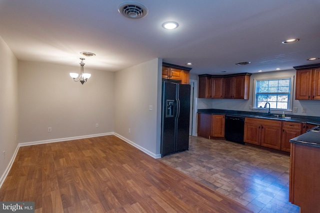 kitchen with dark wood-type flooring, sink, black appliances, pendant lighting, and an inviting chandelier