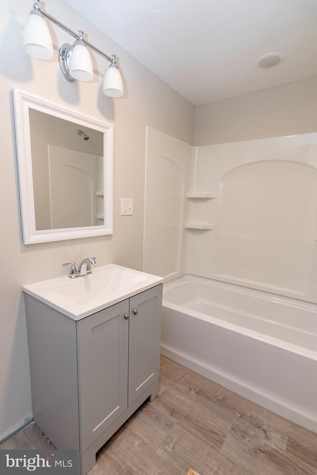 full bath featuring wood finished floors, vanity, and shower / bathtub combination
