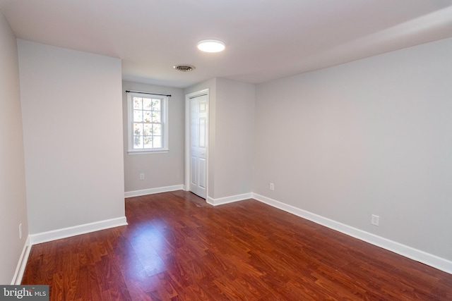 spare room featuring baseboards, dark wood-style floors, and visible vents