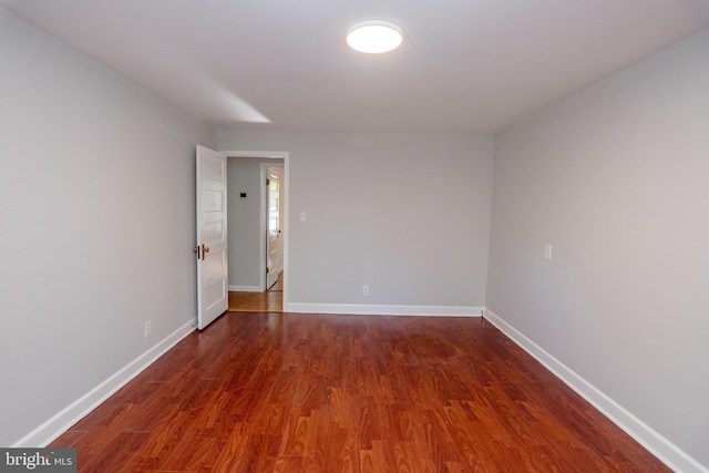 unfurnished room with dark wood-style flooring and baseboards