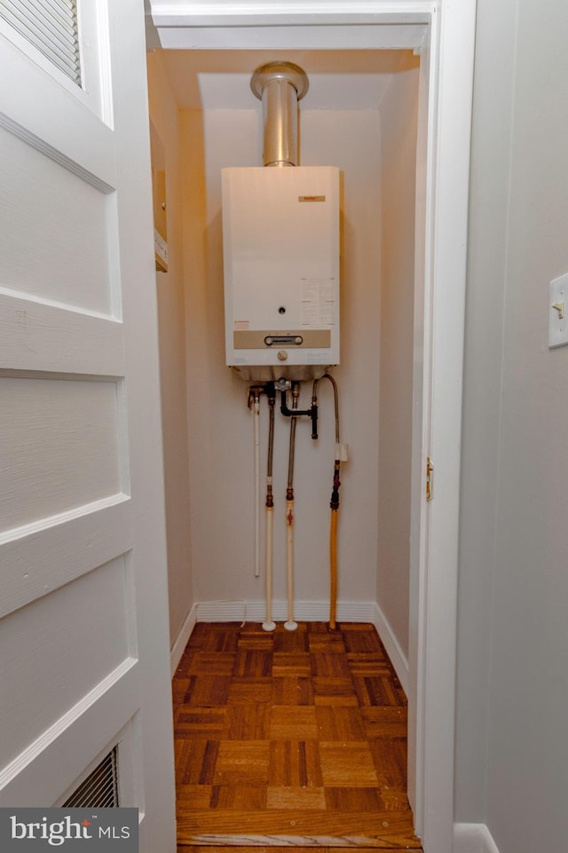 clothes washing area with tankless water heater and baseboards