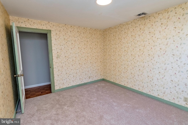 carpeted empty room with visible vents, baseboards, and wallpapered walls
