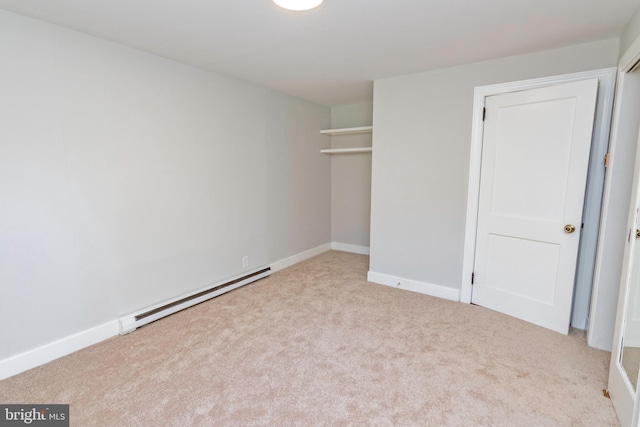 unfurnished bedroom with a closet, a baseboard heating unit, baseboards, and carpet floors