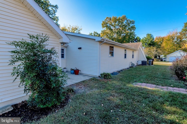 view of side of home featuring central AC and a lawn