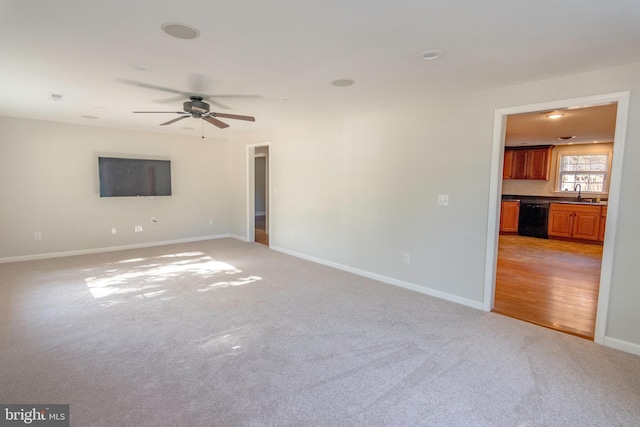 unfurnished room with light carpet, baseboards, a sink, and a ceiling fan