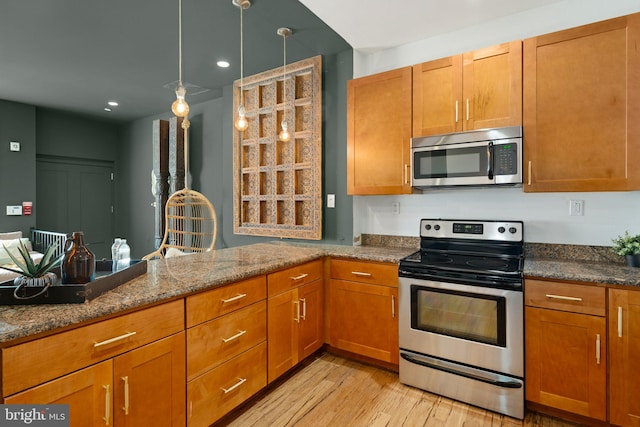 kitchen featuring dark stone counters, light hardwood / wood-style floors, appliances with stainless steel finishes, and pendant lighting