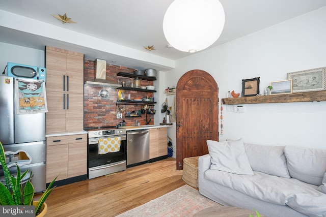 interior space featuring appliances with stainless steel finishes, light wood-type flooring, and wall chimney range hood