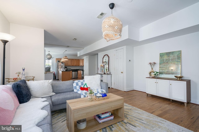 living room featuring wood-type flooring and an inviting chandelier