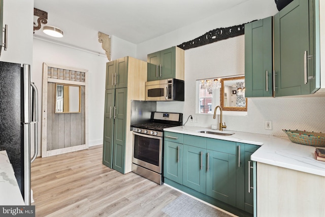 kitchen with sink, green cabinetry, light hardwood / wood-style flooring, backsplash, and stainless steel appliances