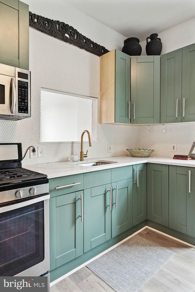 kitchen featuring light hardwood / wood-style floors, appliances with stainless steel finishes, tasteful backsplash, and sink