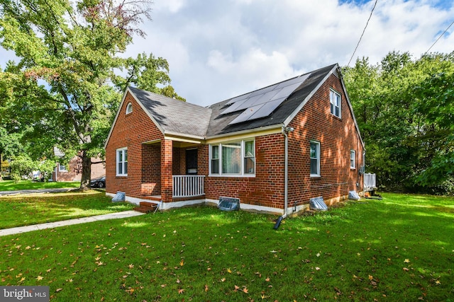 view of front facade with a porch, a front lawn, and solar panels