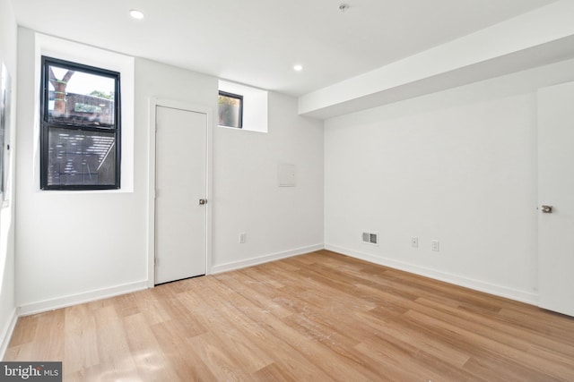 basement featuring light wood-type flooring and a healthy amount of sunlight