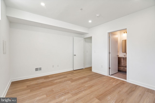 unfurnished bedroom with connected bathroom and light hardwood / wood-style floors