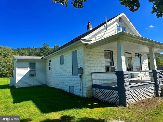 view of side of home featuring covered porch and a yard