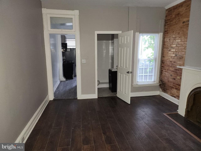 unfurnished living room featuring brick wall and dark hardwood / wood-style flooring