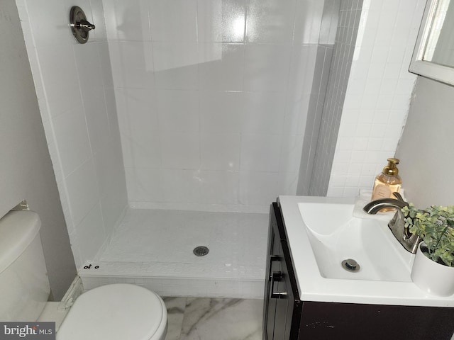 bathroom with a tile shower, vanity, and toilet