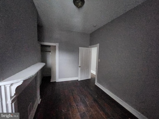 unfurnished bedroom featuring lofted ceiling and dark hardwood / wood-style floors