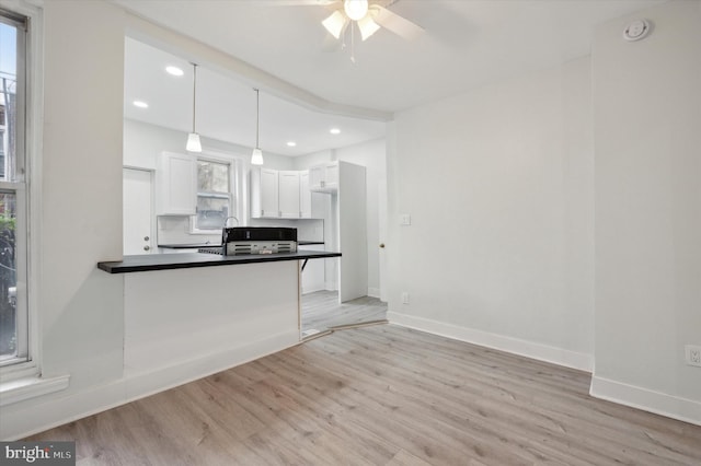 kitchen featuring white cabinets, light hardwood / wood-style floors, hanging light fixtures, and a healthy amount of sunlight