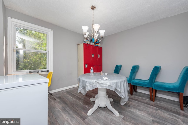 dining room with an inviting chandelier, a textured ceiling, and dark hardwood / wood-style floors