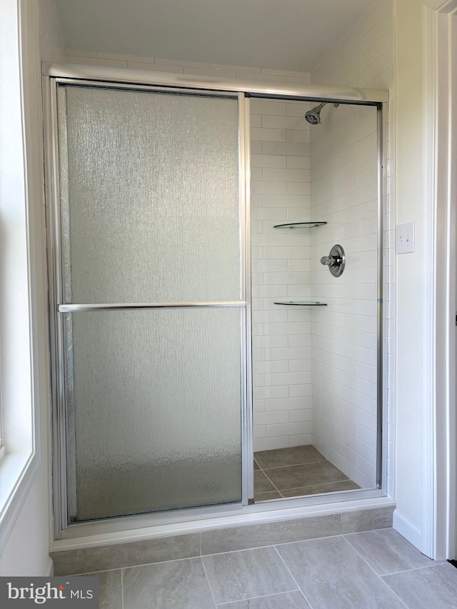 bathroom with a shower with shower door and tile patterned floors