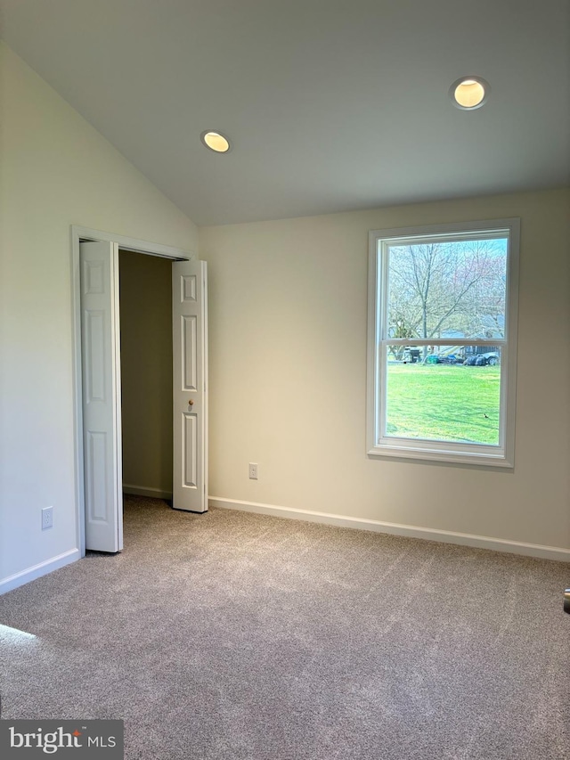 unfurnished bedroom featuring lofted ceiling and light colored carpet