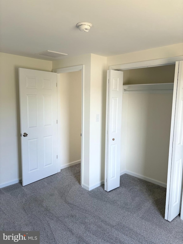 unfurnished bedroom featuring dark carpet and a closet