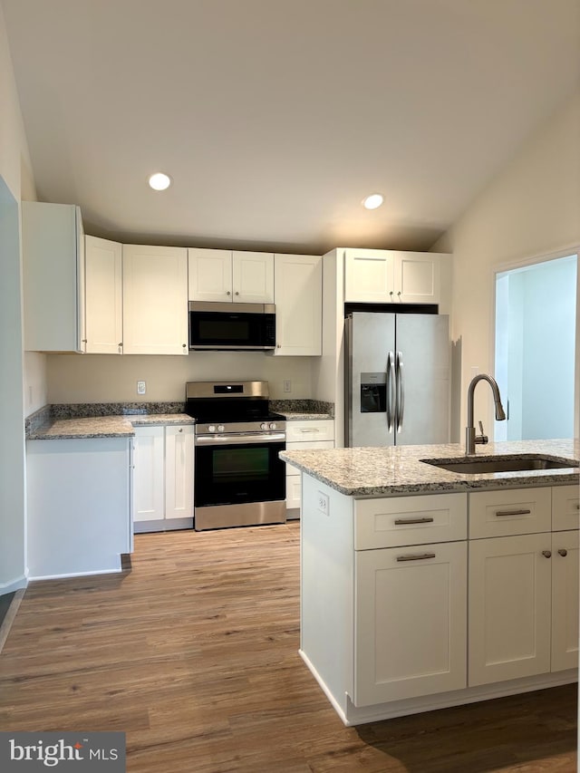 kitchen with appliances with stainless steel finishes, light hardwood / wood-style floors, sink, and white cabinets