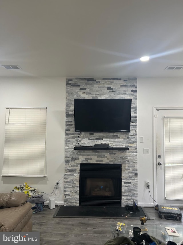 living room with hardwood / wood-style flooring and a stone fireplace