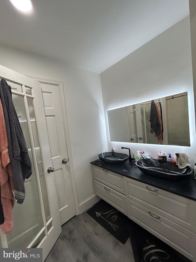 bathroom featuring wood finished floors, a sink, and double vanity