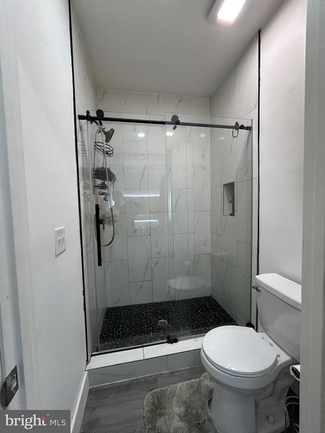 full bathroom featuring wood finished floors, toilet, and a stall shower
