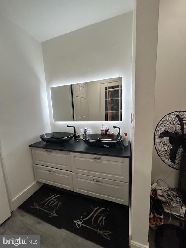 bathroom featuring baseboards, a sink, and double vanity