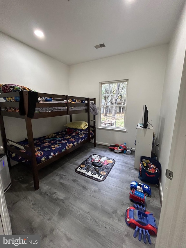 bedroom with wood finished floors, visible vents, and baseboards