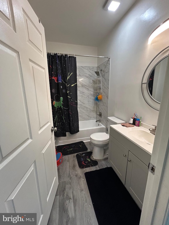 full bathroom featuring wood finished floors, shower / bath combo with shower curtain, toilet, and vanity
