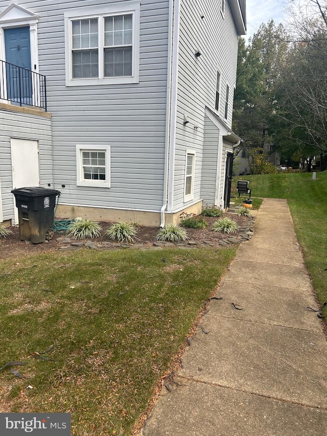 view of side of home with a yard and a balcony