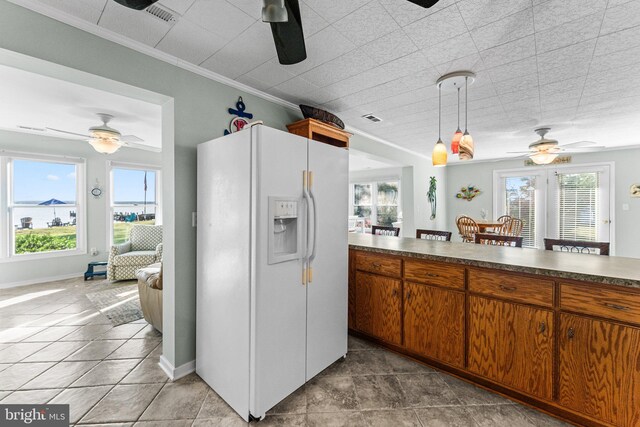 kitchen featuring crown molding, hanging light fixtures, white fridge with ice dispenser, and plenty of natural light