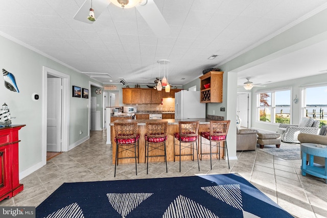 dining space with bar area, ornamental molding, ceiling fan, and light tile patterned floors