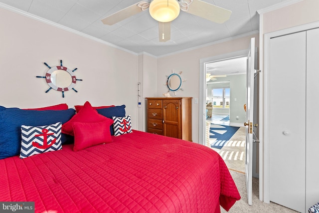 carpeted bedroom with ornamental molding, ceiling fan, and a closet