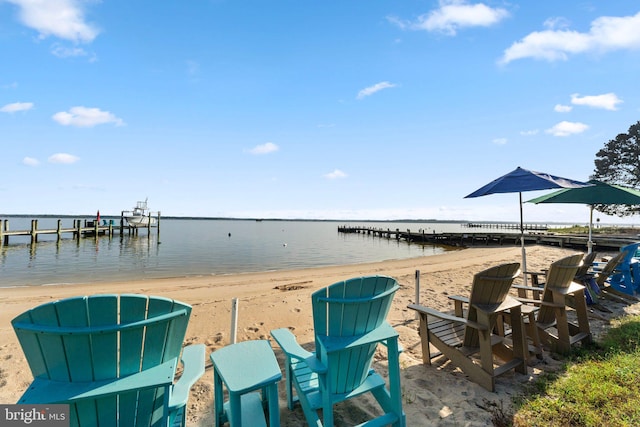 view of dock with a beach view and a water view