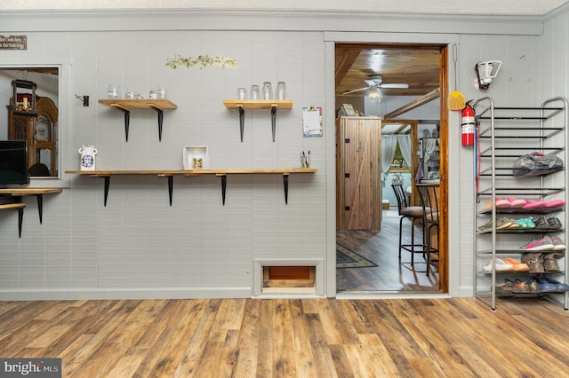 kitchen featuring ceiling fan, wooden walls, crown molding, and hardwood / wood-style floors