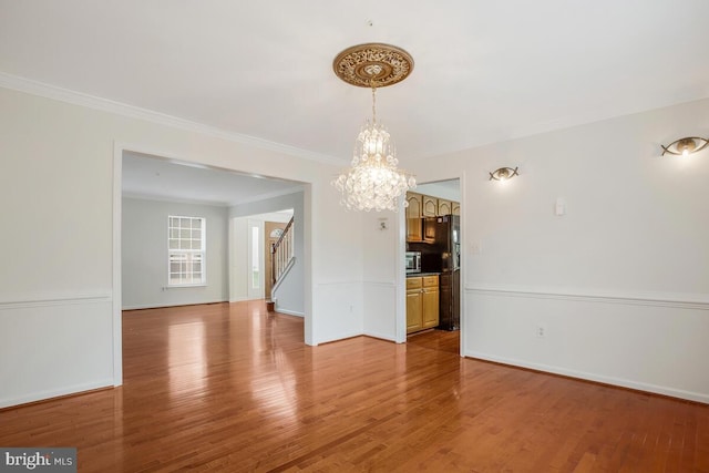 unfurnished room with light wood-type flooring, a chandelier, and crown molding