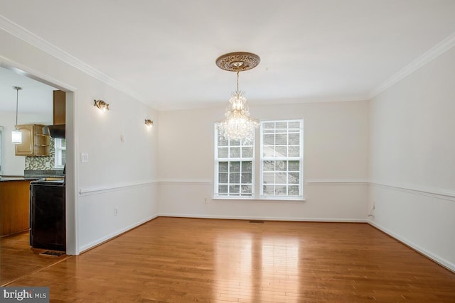 unfurnished dining area featuring crown molding, an inviting chandelier, and hardwood / wood-style flooring