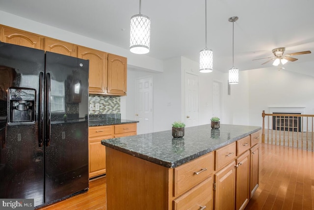 kitchen featuring tasteful backsplash, decorative light fixtures, light hardwood / wood-style flooring, black refrigerator with ice dispenser, and a center island