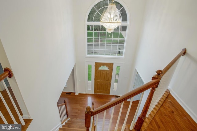 entryway featuring a high ceiling, a chandelier, and wood-type flooring